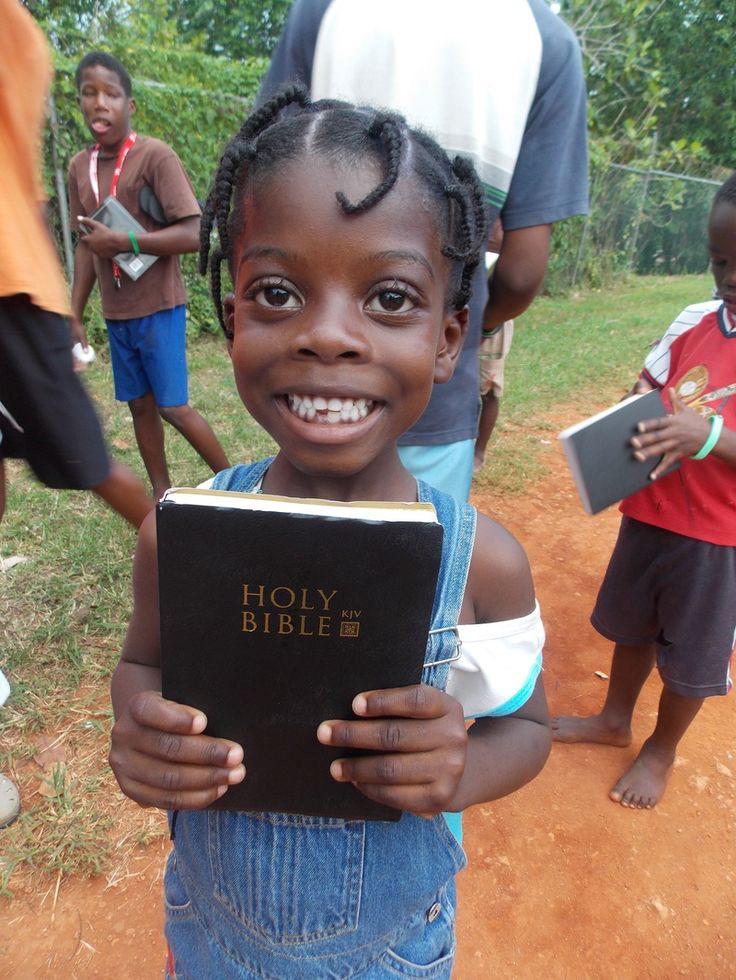 Joyful young girl holding a Holy Bible during Bible distribution in Uganda